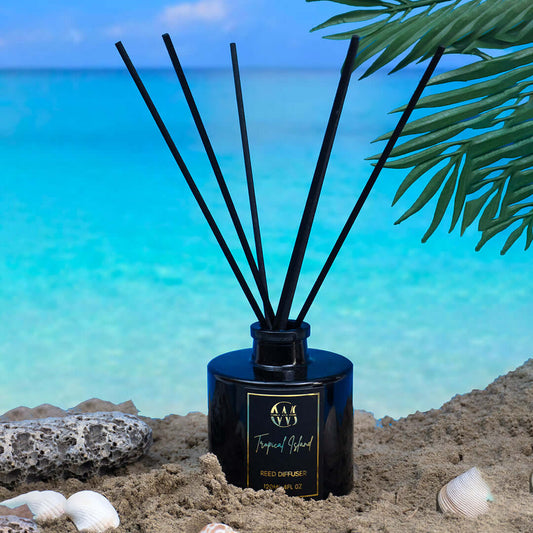 Tropical Island Reed Diffuser on beach sand with ocean backdrop, offering an energizing scent experience.